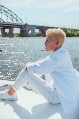 Yakışıklı beyaz çocuk yatta şarkı söylüyor.