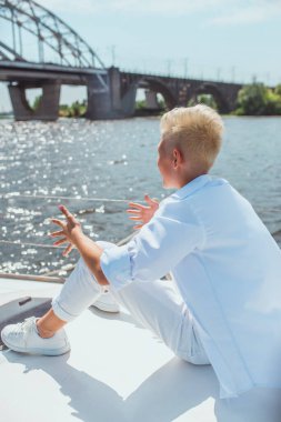 Yakışıklı beyaz çocuk yatta şarkı söylüyor.