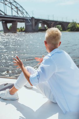 Yakışıklı beyaz çocuk yatta şarkı söylüyor.