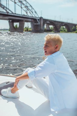 Yakışıklı beyaz çocuk yatta şarkı söylüyor.