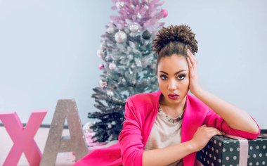 Noel ağacının yanındaki üzgün Afro-Amerikalı kadın Noel hediyesi yüzünden hayal kırıklığına uğradı. Noel, yeni yıl, hüsran, mutluluk, tatil konsepti