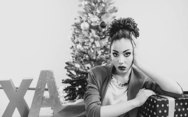 sad afro american woman by the Christmas tree disappointed by christmas present. Christmas, new year, frustration, happiness, holidays concept