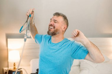 Yatak odasındaki yatakta oturan CPAP makinesini kullandıktan sonra kronik solunum problemi olan mutlu dinlenmiş bir adam. Sağlık, CPAP, uyku apnesi terapisi, horlama konsepti