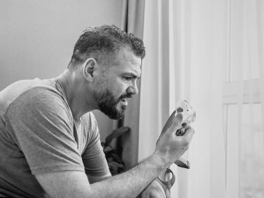 Mutsuz, şok olmuş, kronik solunum sorunu olan bir adam yatak odasında CPAP makinesini kullanarak şaşırdı. Sağlık, CPAP, uyku apnesi terapisi, horlama konsepti