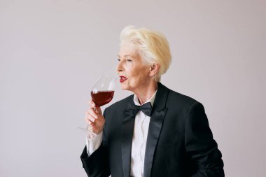Smokinli, camlı ya da kırmızı şaraplı son sınıf şarap garsonu kadın. İçecek, olgun, tarz kavramı