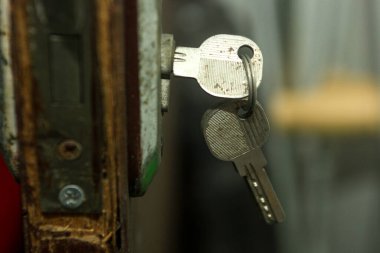 İyi kullanılmış bir kapı kilidine yakın çekim, üzerinde bir çift anahtar asılı, güvenlik, ev, ya da belki geçiş teması önerir.