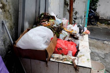 Aşırı yüklü ve kalabalık büyük çöp konteynırları. Çimento ve tuğladan yapılmış