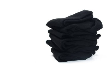 Düz beyaz arka plana karşı katlanmış siyah çorap yığını.