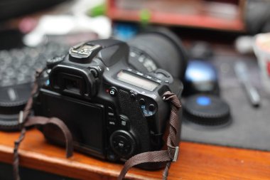 Profesyonel DSLR kamerası ahşap bir masada dinleniyor.