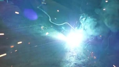 Metal çelik ve demirle yakın çekim işi kaynak makinesi, parlak kıvılcımlar ve çok yavaş çekimde yanıp sönüyor.