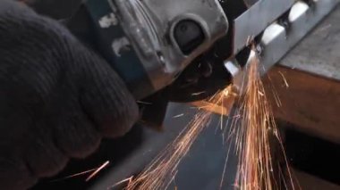 Bir adam dairesel testere ile çalışıyor. Sıcak metalden kıvılcımlar çıkıyor. Yavaş çekim. Yakın çekim.