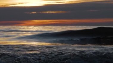 Gün batımında kıyıda küçük dalgalar, yavaş çekim