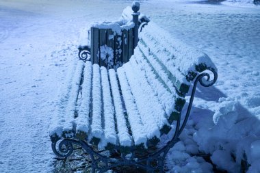 Karlı ahşap bankların olduğu gece fotoğrafı