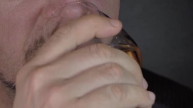 Sakallı bir adam kadehten şarap içer.