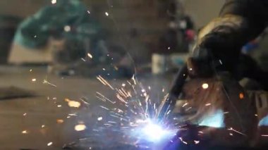 Masadaki kaynakçı bir takım metal parçaları kaynaklıyor. Kaynakçı çalışıyor. Metalle çalışmak