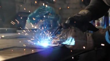 Masadaki kaynakçı bir takım metal parçaları kaynaklıyor. Kaynakçı çalışıyor. Metalle çalışmak
