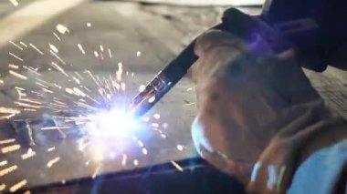 Masadaki kaynakçı bir takım metal parçaları kaynaklıyor. Kaynakçı çalışıyor. Metalle çalışmak