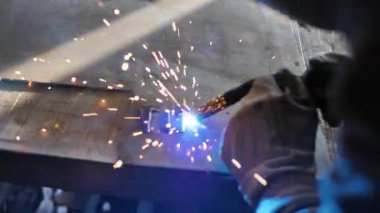 Masadaki kaynakçı bir takım metal parçaları kaynaklıyor. Kaynakçı çalışıyor. Metalle çalışmak