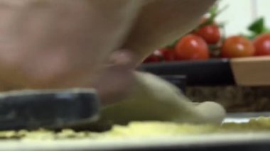 Adam pizzayı elleriyle yoğuruyor.