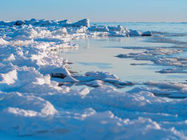 Soğuk kış kıyısı. Deniz kenarındaki buz parçaları. Küçük bulutlu mavi gökyüzü