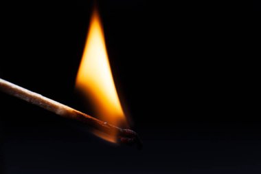 Dikkat, tehlikeli bir şekilde ormanda bir kibrit, kuru ot, siyah arka planda büyük bir alev.