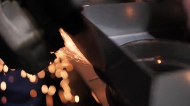 Metal parçaları incelerken kıvılcımlar her yöne doğru uçar. Fabrikada metal işleme. El işi.