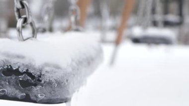 Oyun alanı kışın kapalıdır. Salıncak rüzgarda hareket ediyor. Salıncakta kar ve buz var.
