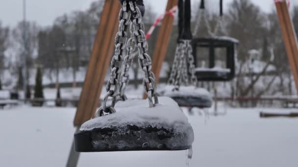 遊び場は冬に閉鎖されます 風の中でスイングが動きます スイングには雪と氷があります — ストック動画