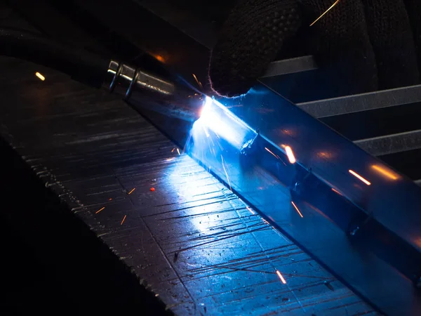 Metal kaynakçı, koruyucu ekipmanlı bir fabrikada çelik kaynakçıyla çalışıyor. Metal yapıların imalatı ve tamirat ve inşaat hizmetleri el işçiliği kavramına göre.