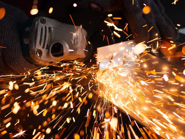 Man is working with a circular saw. Sparks fly from hot metal. Man worked hard on steel