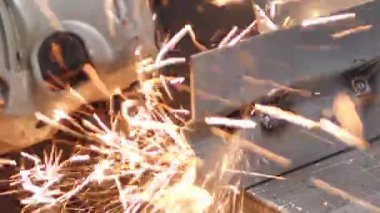 Adam dairesel testere ile çalışıyor. Sıcak metalden kıvılcımlar çıkıyor. Adam çelik üzerinde çok çalıştı.