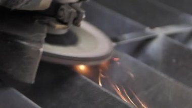 Adam dairesel testere ile çalışıyor. Sıcak metalden kıvılcımlar çıkıyor. Adam çelik üzerinde çok çalıştı.