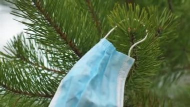 Tıbbi tek kullanımlık mavi koruyucu maske çam kürklerinde, Coronavirus Covid-19 virüs atığında rüzgarda savruluyor. Çöp toplama. Yeşil gezegen Dünya