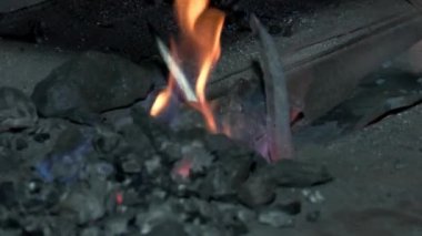 Yangında demirci, metali ısıtarak bir ürün oluşturur. Fırında kırmızı kömür var.