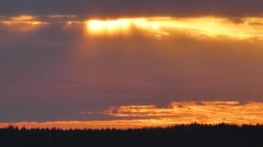 Arka plan bulanık. Yağmur bulutlarının ardında inanılmaz dramatik bir gün batımı. Büyük parlak kırmızı bir güneş ufukta hareket ediyor. Güneşin batışına karşı altın gökyüzü ve kıvrımlı bulutlarla çarpıcı bir manzara..