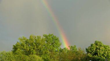 Gün batımında yağmur bulutları üzerinde gökkuşağı