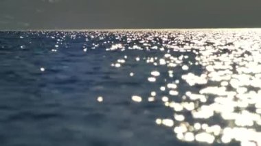 Sinemada bulanık ortam. Dalgalar fotoğraf merceğine yansıyor. Sıcak hava gün batımında titreşir. Küçük dalgalarla deniz ufku.