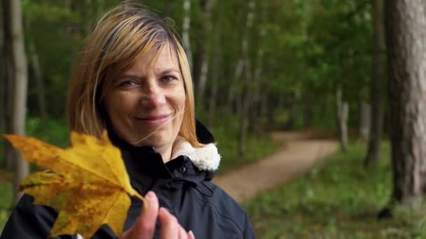 Γυναίκα Χαμογελάει Ένα Φύλλο Σφενδάμου Στο Χέρι Της — Αρχείο Βίντεο