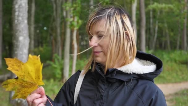 Mujer Sonríe Con Una Hoja Arce Mano — Vídeos de Stock