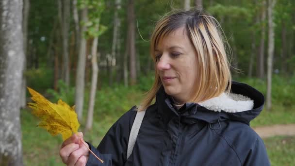 Vrouw Glimlacht Met Een Esdoornblad Haar Hand — Stockvideo