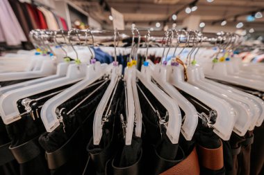 Bir moda mağazasında plastik askıların üzerinde düzgünce düzenlenmiş dairesel giysi rafı, çeşitli boyutlarda ve tarzlarda pantolonları iyi organize edilmiş bir perakende vitrininde sergiliyor..