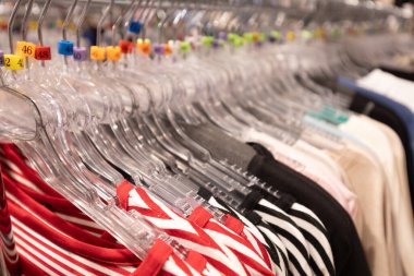 Bir moda mağazasında plastik askıların üzerinde düzgünce düzenlenmiş dairesel giysi rafı, çeşitli boyutlarda ve tarzlarda pantolonları iyi organize edilmiş bir perakende vitrininde sergiliyor..