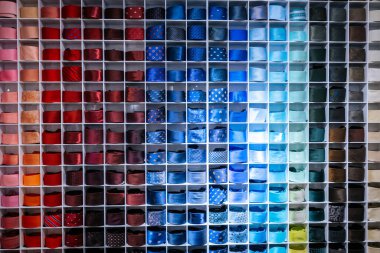 Renkli, kırmızı, bordo, mavi, yeşil, yeşil ve kahverengi renklere göre düzenlenmiş kıvrılmış kravatların canlı duvar görüntüsü bir erkek moda mağazasında düzenli olarak düzenlenir..