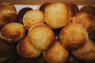 Ahşap tepsilerde dizilmiş çoklu altın sarısı ekmek rulolarının yakın çekim görüntüsü. Yeni pişmiş ve mutfak tezgahında servis için hazır..