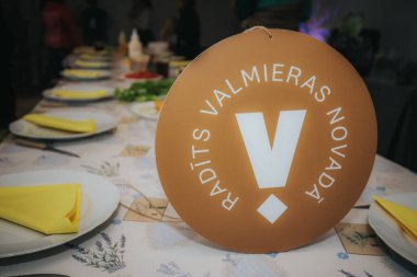 Kovboy şapkalı bir kadın, uzun bir masada diğerleriyle hamburger yemekten hoşlanır. Odak ve sağlıklı yiyeceklerle dolu bir köy yemeği anı yakalar..