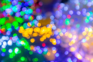 Değişik renklerde parlak bokeh ışıkları yeşil, sarı, mavi ve mor tonlarını harmanlayarak neşeli anlar ve kutlamalar için mükemmel bir ortam yaratır.