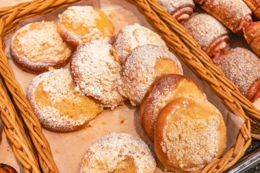 Toz şekere bulanmış çeşitli hamur işleri dokuma sepetinde güzelce sergileniyor, hoşgörüye davet ediliyor ve rahat bir fırın ortamının havasını güzelleştiriyor.