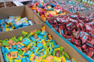 Valmier, Letonya - 24 Kasım 2025: Parlak ambalajlı çeşitli şekerler pazardaki karton kutuları doldurarak görsel olarak çekici bir şeker gösterisi yarattı