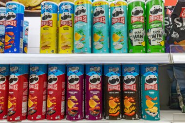Valmier, Letonya - 24 Kasım 2025: Pringles kutularının değişik aromalı canlı çeşitleri süpermarket raflarında markalaşmak için fotokopi alanı ile birlikte sergilendi