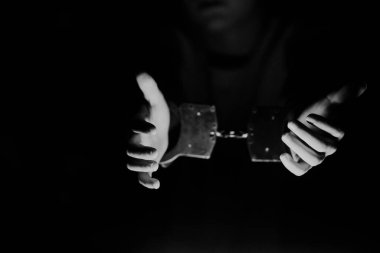 Elleri kelepçeli bir çift elin loş bir ortamda uzandığı, esaret, gerilim ve özgürleşme arzusunu çağrıştırdığı gösteriliyor.